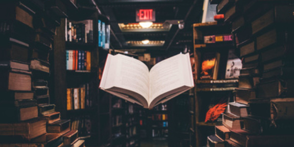 An open book levitating in the middle of a library