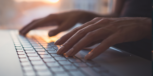 Close-up of a woman's hands typing on a laptop keyboard