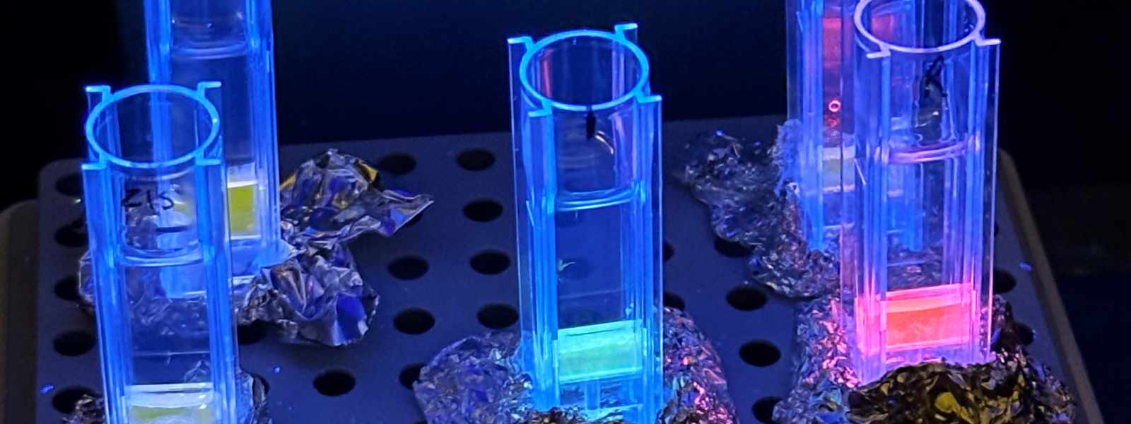 Supraparticles suspended in water solutions under UV light.